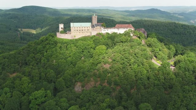 Close drone flight to the old German castle "Wartburg" in Eisenach, Thuringia - arial of the beautiful nature landscape with range forest, 4K 