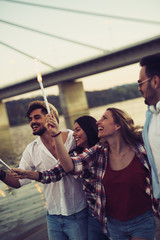 Happy group of friends lighting sparklers and enjoying freedom