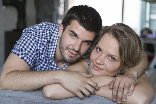 Portrait of smiling young couple at sofa in the living room