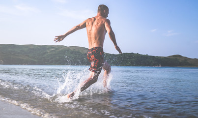 Muscular young man dives from the shore in to the sea