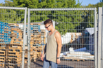 Young man in sunglasses posing on urban background, hipster male model  