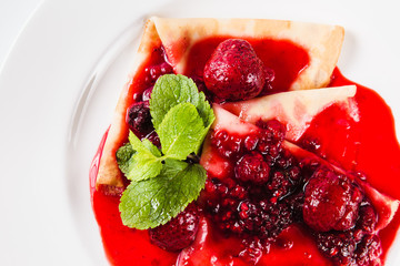 Sweet dessert. Pancakes with berry of the strawberry and raspberry sauce (top view close)
