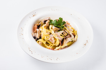 Pasta with chicken and mushrooms on a round white plate on a light background (close)