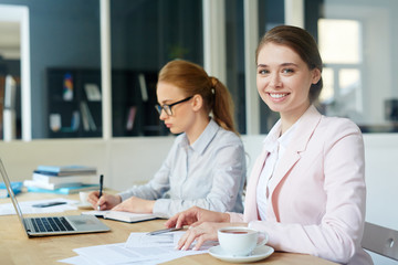 Female analyst reading paper documents with colleague on background