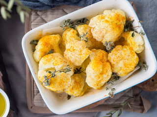 Baked cauliflower with turmeric and marjoram on rustic background. Lunch with vegetables
