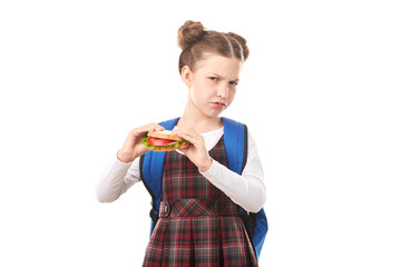 Portrait of cute girl in school uniform eating sandwich against white background