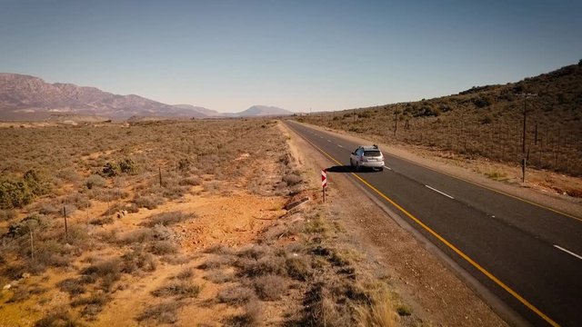 car driving down a long road in the semi desert, aerial