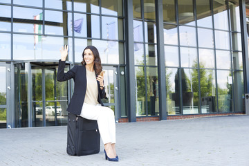 Young businesswoman portrait. Full length shot of a young businesswoman using her mobile phone while waiting for a taxi in front of the office building.