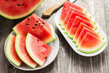 Watermelon slices on white plate on wooden background. 