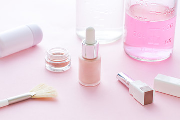 Cosmetics bottles on the pink background with flowers.Close up
