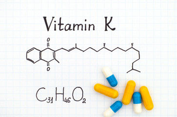 Chemical formula of Vitamin K and some pills.