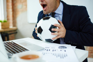Businessman watching online football match broadcast in office