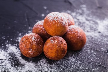 Curd balls sprinkled with sugar buds on a dark background