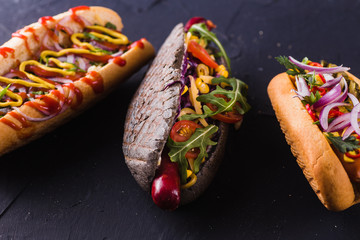 three hot dog on a dark background (close)