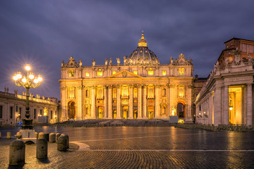 Fototapeta na wymiar Sunrise over the St. Peters Basilica in Vatican City. Morning at the most famous landmark, empty of people street, cloudy sky.