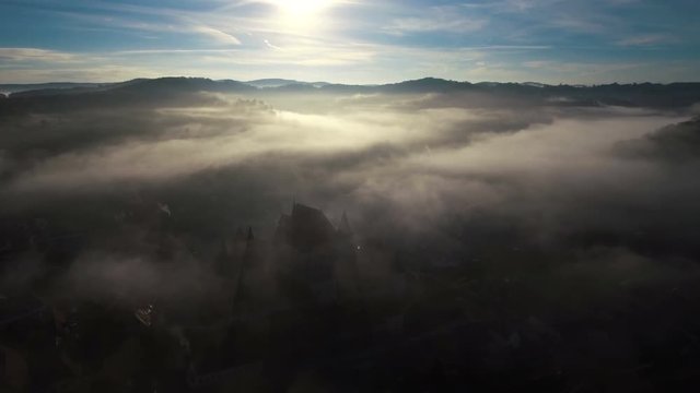 Aerial drone slow shot over remote village in early morning. 4k footage. Transylvania, Romania.	Autumn fog rising and revealing isolated houses and colorful trees.