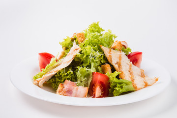 salad with bacon, tomatoes and croutons on a white plate