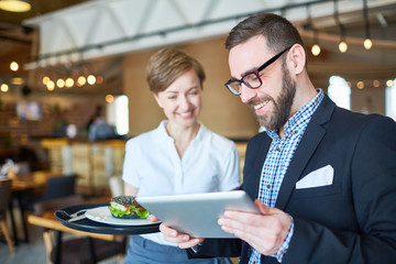 Businessman choosing business lunch from electronic menu in restaurant