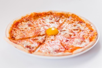 sliced pizza with egg yolk on a white plate on a light background.