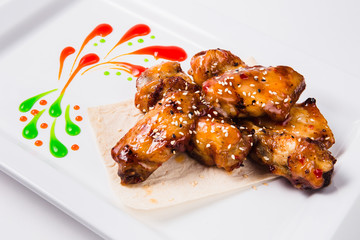 Fried chicken wings with sauce on a white plate (close)