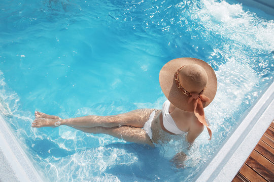 Woman in beach hat enjoying in swimming pool on Tropical Resort. Exotic Paradise. Travel, Tourism and Vacations Concept.
