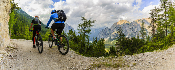 Mountain biking couple with bikes on track, Cortina d'Ampezzo, Dolomites, Italy