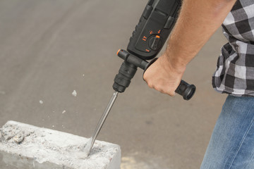 Drill beats concrete with pieces of dust and stone