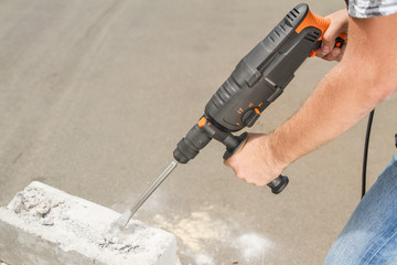Drill beats concrete with pieces of dust and stone