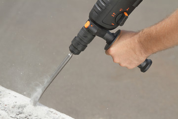 Drill beats concrete with pieces of dust and stone
