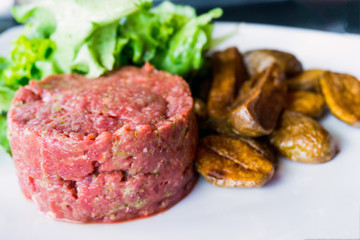 Raw beef classic steak tartare on white plate