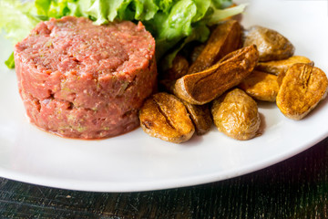 Raw beef classic steak tartare on white plate
