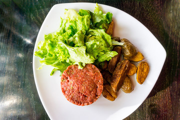 Raw beef classic steak tartare on white plate