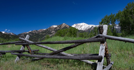 Snowcovered mountainrange landscape with split rail wooden fence foreground