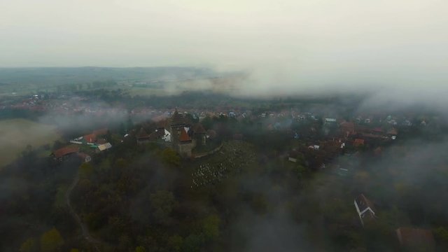 4k drone slow shot over medieval church and saxon houses in Viscri village.	Autumn countryside view in foreground and yellow valley in background. Transylvania, Romania. 4k footage. 