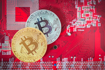 Golden and silver bitcoin on red circuit motherboard,Technology and finance concept,Selective focus