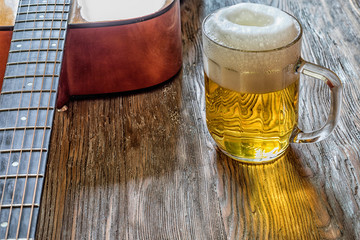 Acoustic guitar and beer on an old wooden background