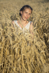 Naklejka na ściany i meble Beautiful woman in wheat at sunset.