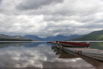 Boats on the Pier with Mountainrange background and mirror-like lake McDonald with Cloud reflections