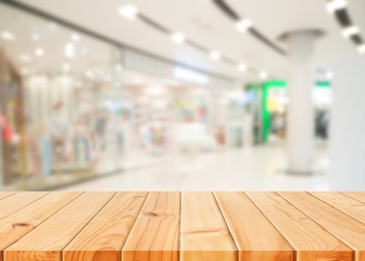 Wooden table in front of abstract blurred shopping mall background. For present your products.