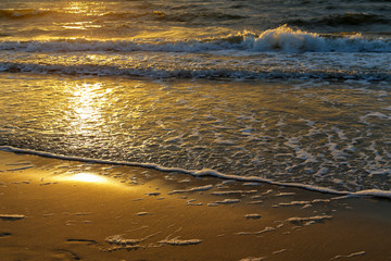 The rays of the sunset reflects on a sea waves