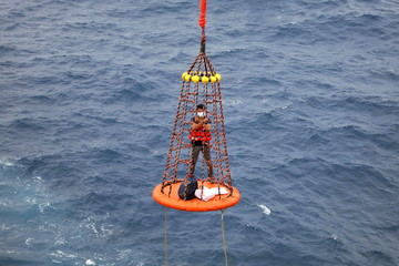Workers are lifted by the crane to the offshore platform, Transfer crews by personal basket from the platform to crews boat © chanjaok1