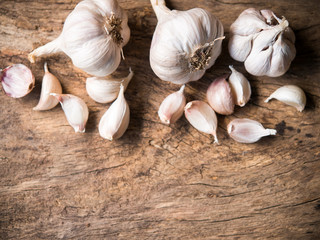Garlic cloves and bulbs on wood table in top view with copy space.