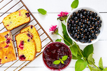 Delicate tasty curd cake with black currant, ripe berries and jam on a white wooden background. Top view.