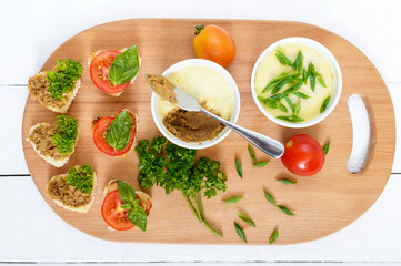 Delicate pate from chicken liver in ceramic bowls. Canape on the cutting board. Light snacks. Top view.