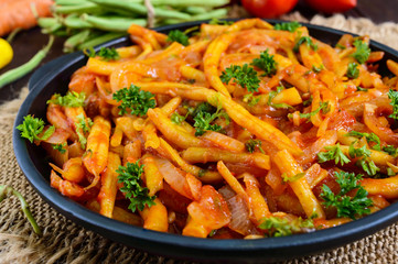 Spicy  green beans stewed with onions, carrots in tomato sauce. Serve on a cast-iron frying pan