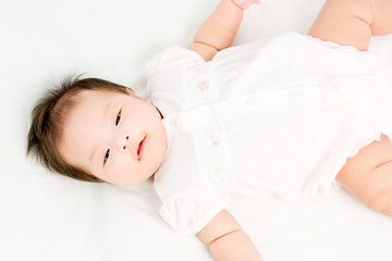 Portrait of a little adorable infant baby girl lying on back on the blanket