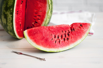 Slice of watermelon on a light rustic wooden background.
