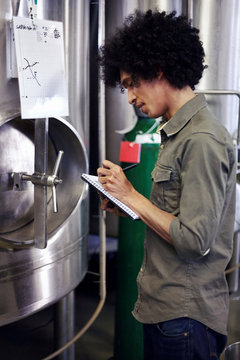Brewmaster by the metal vats in a brewery
