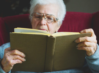 Older woman holding book and reading with homemade eyeglasses