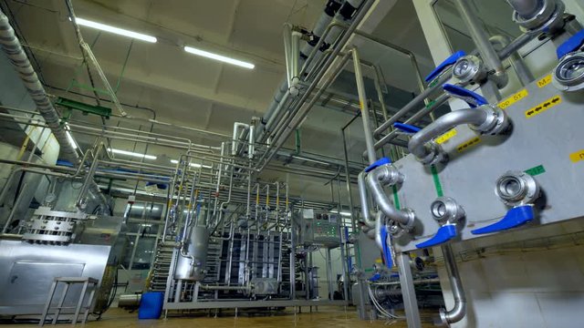 A distant view at all piping equipment inside a dairy factory workroom. 4K.